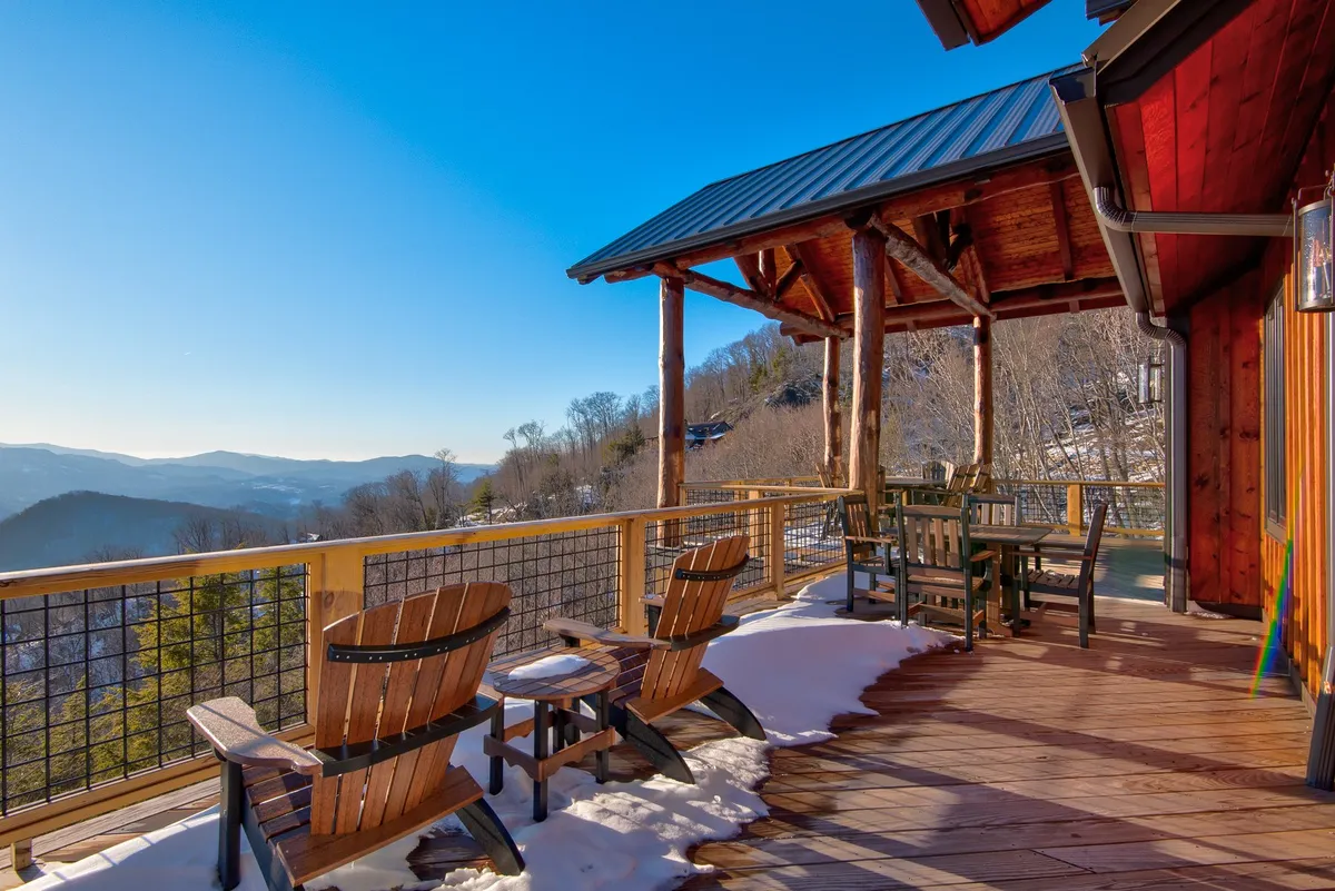 A spacious wooden deck set against a backdrop of sweeping mountain views. Adirondack chairs and a dining table invite guests to relax, dine al fresco, or simply enjoy the majestic scenery. The tranquil setting is perfect for sipping morning coffee or gathering in the evening under the stars.