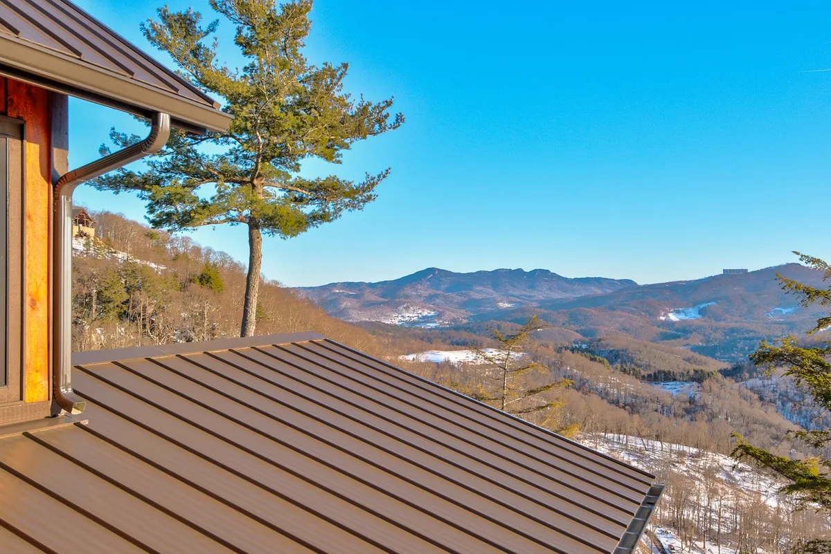 This image captures a striking mountain view framed by a tree and the home’s roofline, suggesting the vastness of the surrounding landscape. It evokes a sense of adventure and the untamed beauty waiting to be explored just beyond the doorstep.