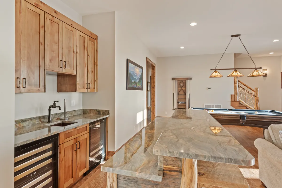 This image showcases the open-concept kitchen featuring a granite-topped island, warm wooden cabinetry, and inviting lighting fixtures. The space exudes a welcoming ambiance designed for both cooking and socializing, with bar stools for casual gatherings and ample counter space for meal prep or conversation.