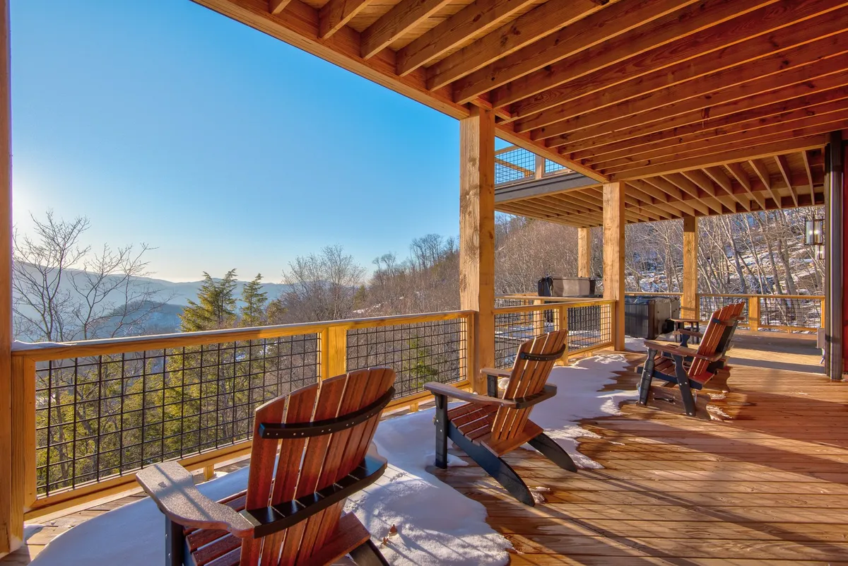 A cozy deck with Adirondack chairs positioned to take in the panoramic mountain vistas. The warm wooden elements and open sky create an inviting outdoor space for relaxation, conversation, or stargazing in the evening.