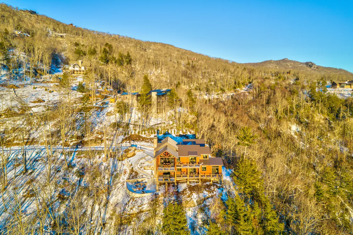 An exterior view of the house framed by snow-covered ground and tall trees, suggesting a peaceful environment. The image hints at the broader community and natural setting accessible to guests, with a suggestion of outdoor activities and scenic tranquility.